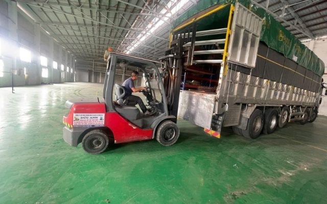 Kỹ thuật viên lái xe nâng hàng tải trọng lớn trong kho xưởng