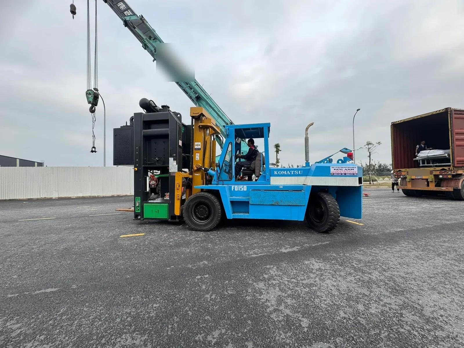 Xe nâng Komatsu FD150 15 tấn mang khối máy lớn màu đen cạnh xe cẩu bánh lốp tại Xe Nâng Đức Anh