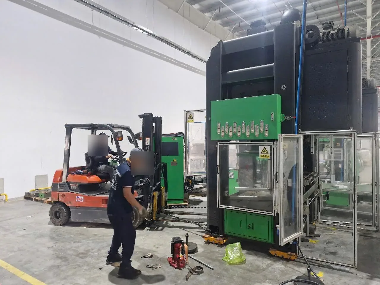 Xe nâng điện và thợ phối hợp đưa máy dập có cửa kính an toàn vào vị trí tại Xe Nâng Đức Anh