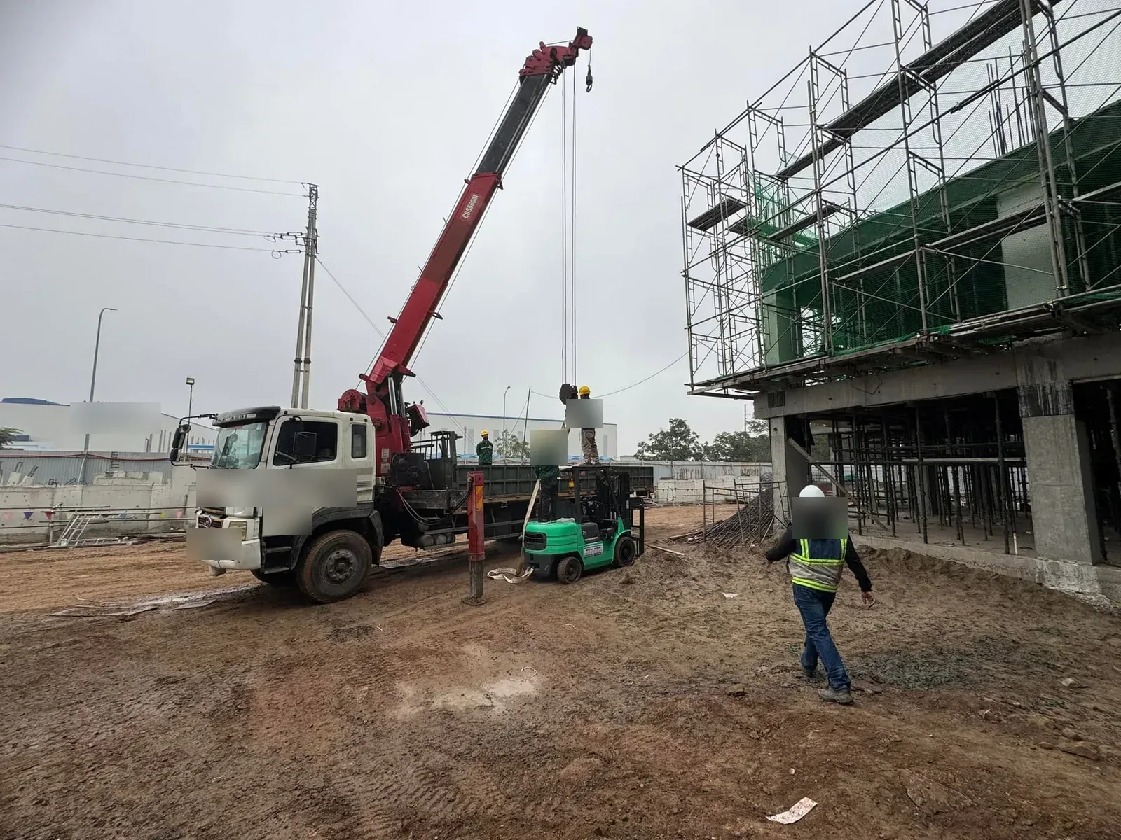 Xe tải gắn cẩu hạ xe nâng xuống công trường nhà khung đang xây tại Xe Nâng Đức Anh