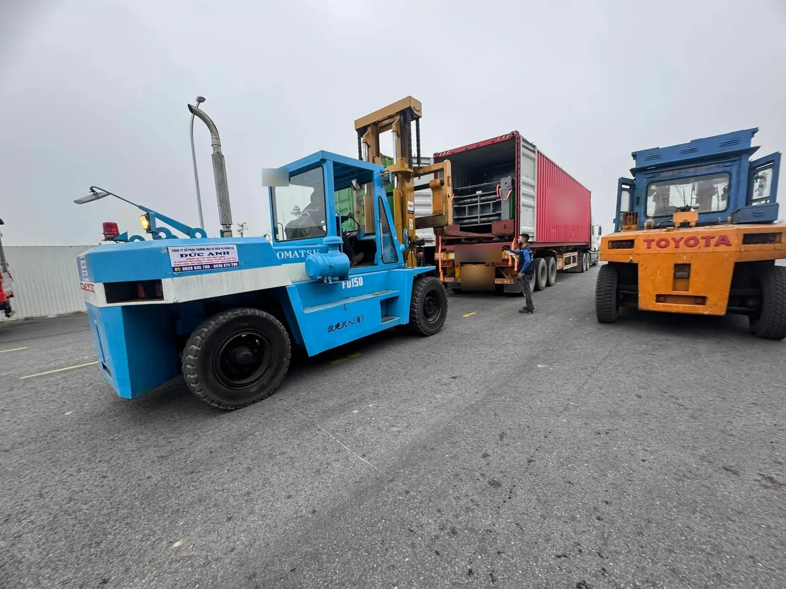 Xe nâng Komatsu FD150 15 tấn đưa kiện máy nặng ra khỏi container 40ft bên cạnh xe nâng Toyota tại Xe Nâng Đức Anh