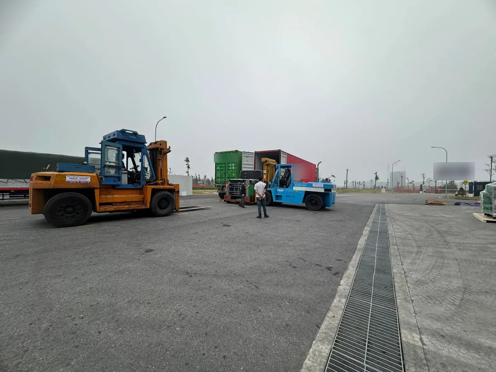 Toàn cảnh hai xe nâng hạng nặng làm việc cạnh container trên bãi chứa hàng tại Xe Nâng Đức Anh