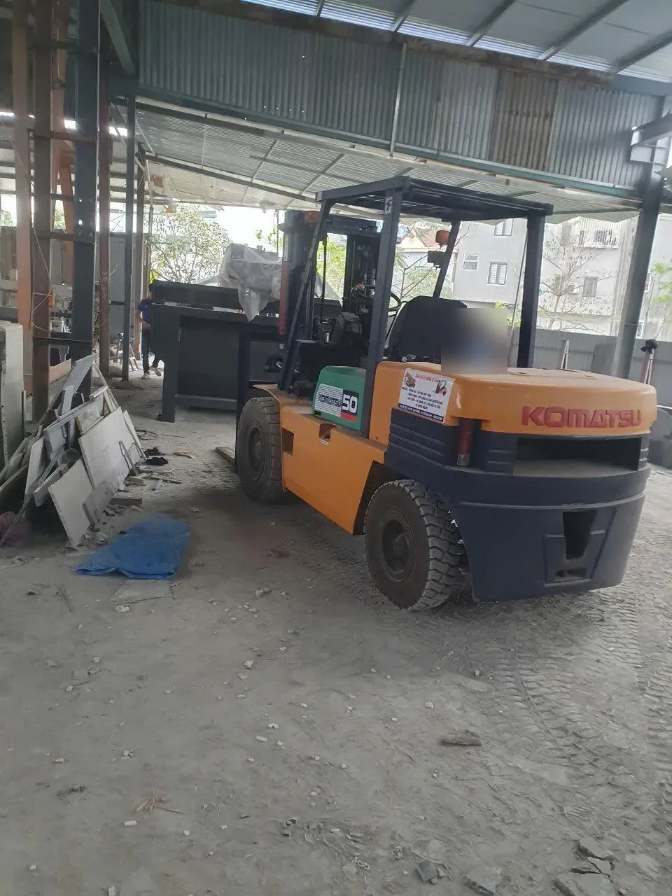 Xe nâng dầu Komatsu đứng trong xưởng gia công đá có mái tôn và cầu trục tại Xe Nâng Đức Anh