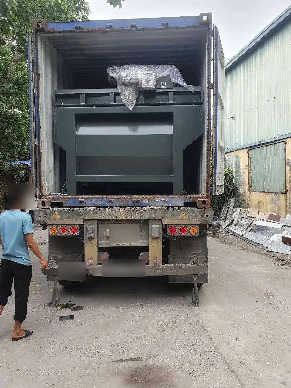 Container chở máy gia công đá đỗ cạnh xưởng, máy bọc nilon nằm trong thùng tại Xe Nâng Đức Anh