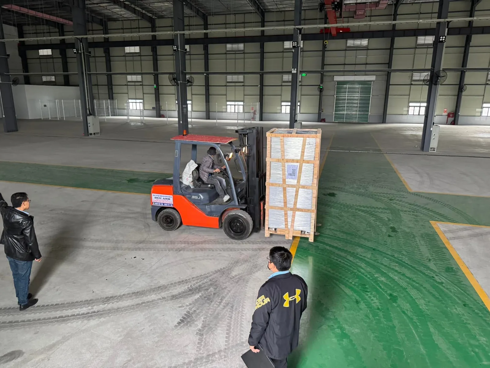 Xe nâng dầu hạ kiện kính xuống sát vạch sàn có người giám sát tại Xe Nâng Đức Anh