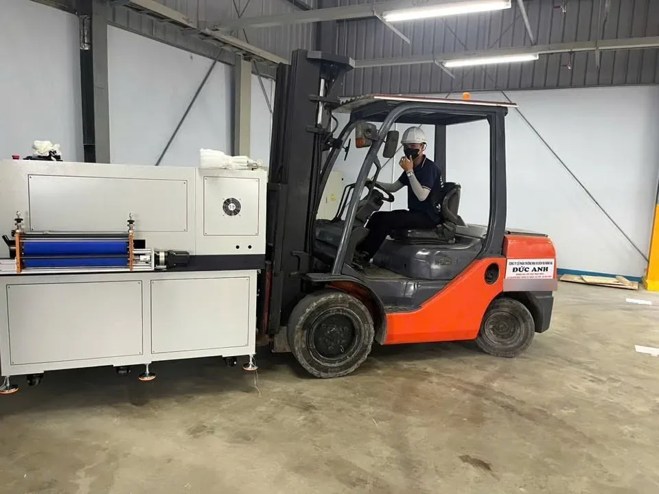 Cận cảnh càng xe nâng giữ máy công nghiệp có chân đế bánh xe khi di chuyển trong nhà máy điện tử