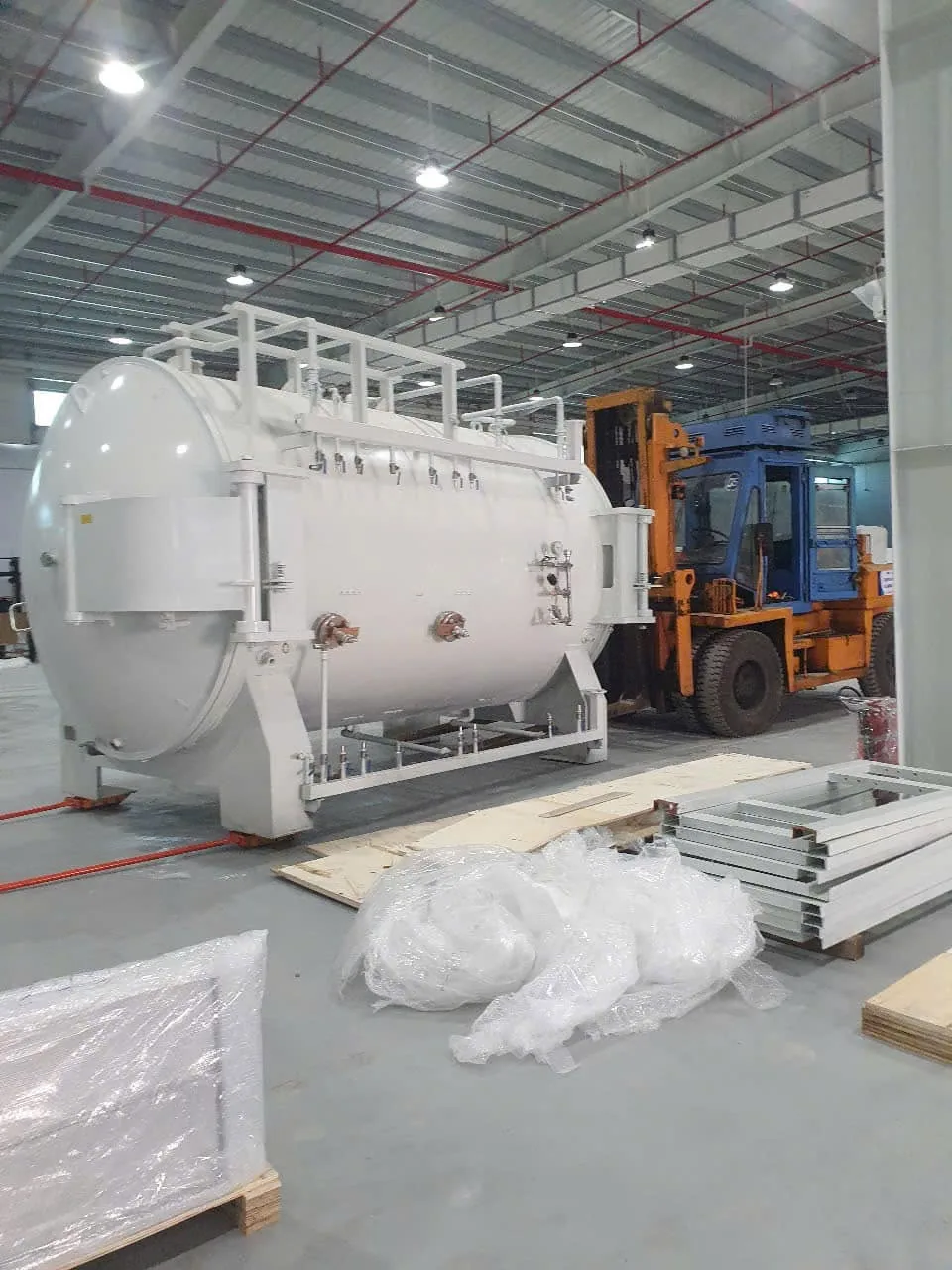 Xe nâng dầu cỡ lớn đứng cạnh bồn áp lực nằm ngang trong nhà xưởng mới tại Xe Nâng Đức Anh