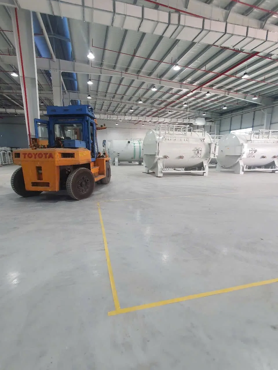 Xe nâng Toyota di chuyển trong xưởng có hàng nồi hấp áp lực xếp phía sau tại Xe Nâng Đức Anh
