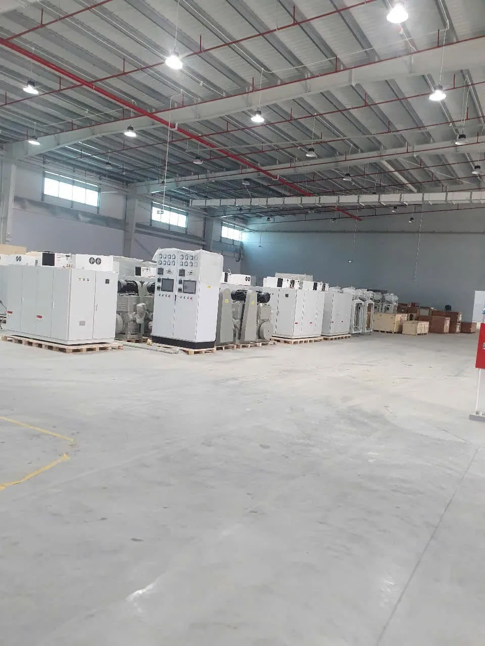 Toàn cảnh nhà xưởng với tủ thiết bị xếp trên pallet cạnh khu đặt bồn áp lực tại Xe Nâng Đức Anh